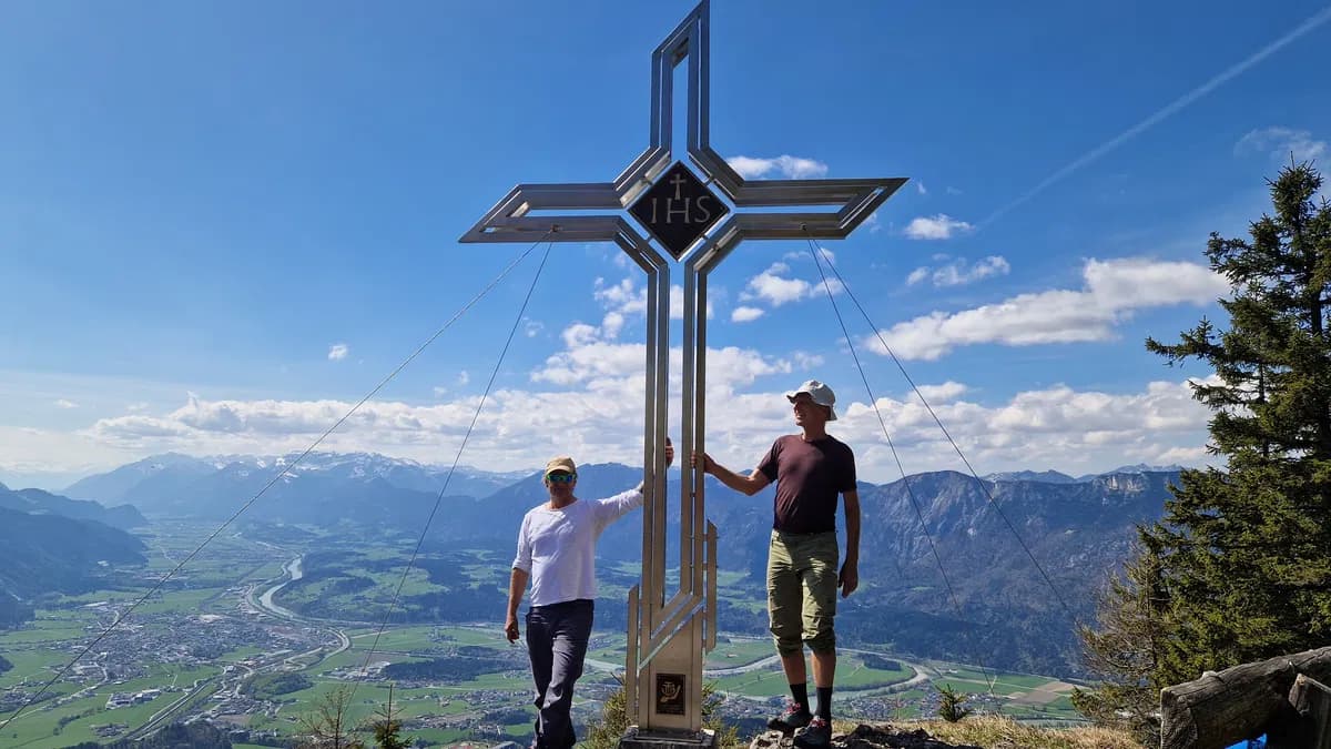 Am Gipfel des Grossen Poelvens geniesst man herrliche Tiefblicke ins Inntal. Gipfelkreuz und zwei Personen daneben.